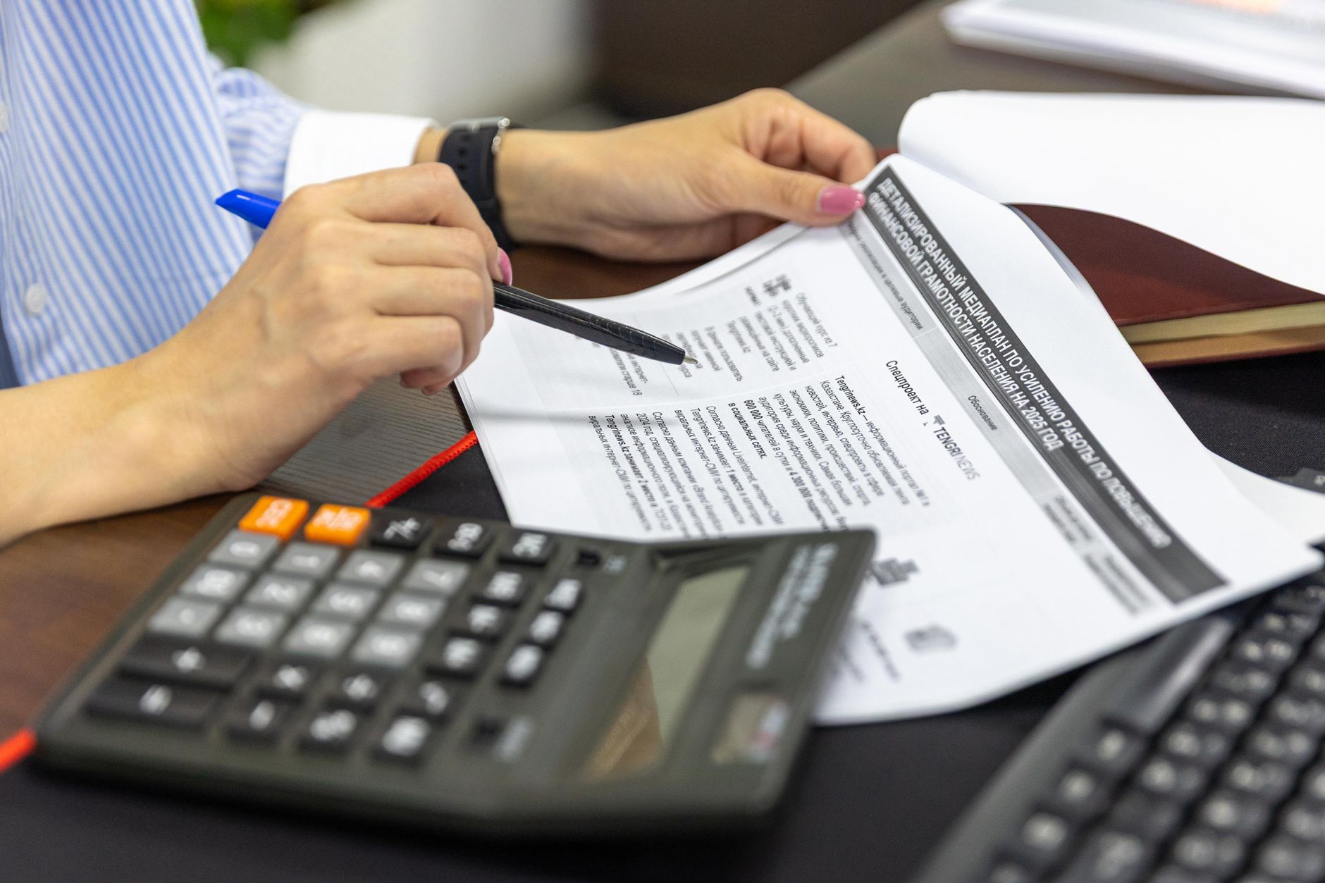 An accountant analysing financial documents with a calculator and pen.